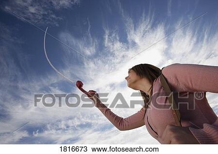 Low angle view of a woman holding phone View Large Photo Image Stock Image - Low angle view of a woman holding phone. Fotosearch