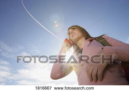 Low angle view of a woman talking on phone View Large Photo Image Stock Photo - Low angle view of a woman talking on phone. Fotosearch