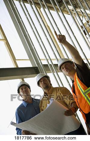 Stock Photograph - Men discussing architecture of a structure. Fotosearch