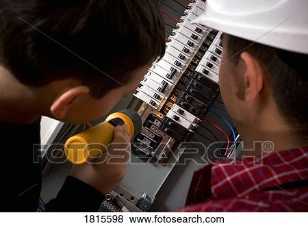 Stock Photo - Men looking at fuse box. Fotosearch