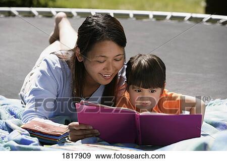 Mother reading with daughter on trampoline View Large Photo Image Stock Photo - Mother reading with daughter on trampoline. Fotosearch