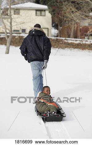Rear view of father pulling son on sled View Large Photo Image Stock Photo - Rear view of father pulling son on sled. Fotosearch