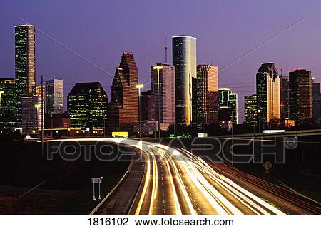 Stock Image - Streaking car lights at night and downtown Houston in USA . Fotosearch