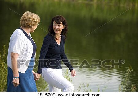 Stock Photo - Two women walking beside a lake. Fotosearch