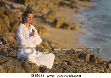 Woman meditating on rocky shore View Large Photo Image Stock Image - Woman meditating on rocky shore. Fotosearch