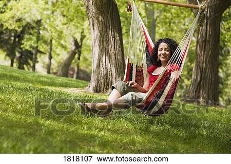Woman sitting on a hammock swing View Large Photo Image Stock Photo - Woman sitting on a hammock swing. Fotosearch
