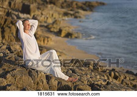Woman stretching on rocky shoreline View Large Photo Image Stock Image - Woman stretching on rocky shoreline. Fotosearch