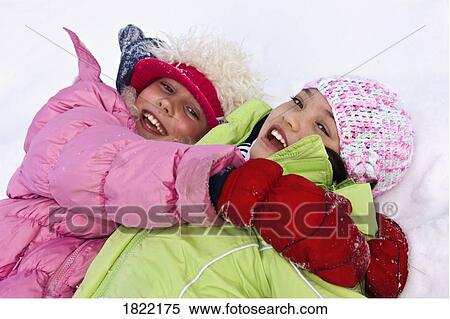 Stock Photography - Girls laying in the snow. Fotosearch
