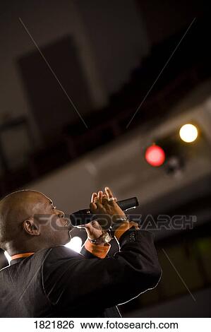 Man speaking into microphone View Large Photo Image Stock Photograph - Man speaking into microphone. Fotosearch