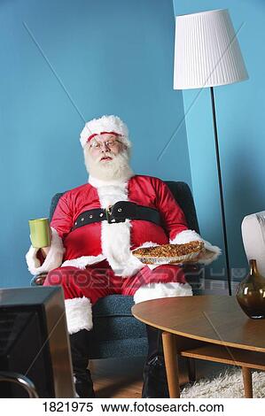 Stock Photography - Santa Claus eating and watching TV. Fotosearch