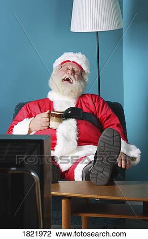Stock Image - Santa Claus laughing and watching TV. Fotosearch