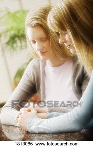 Stock Photograph - Two women praying together. Fotosearch