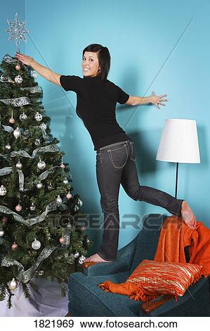 Stock Photo - Woman decorating Christmas tree. Fotosearch