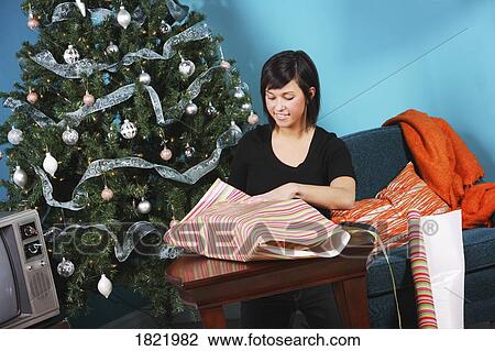 Stock Image - Woman wrapping Christmas gift. Fotosearch