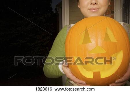 A person holding a carved out pumpkin View Large Photo Image Stock Photograph - A person holding a carved out pumpkin. Fotosearch