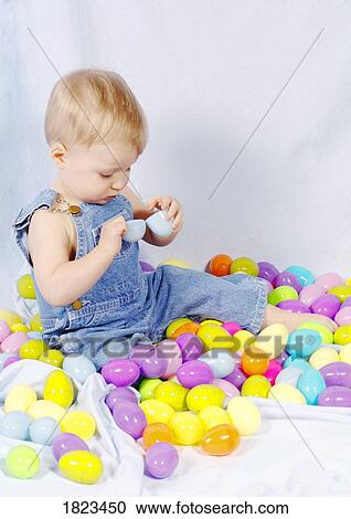 Stock Image - Baby boy sitting in pile of eggs. Fotosearch