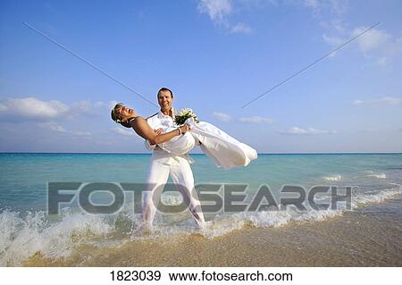 Stock Photo - Bride and groom standing in water. Fotosearch