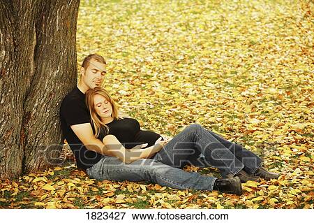 Stock Photo - Couple relaxing by a tree. Fotosearch
