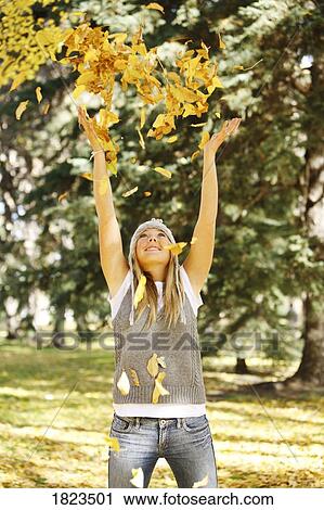 Stock Image - Girl throwing autumn leaves. Fotosearch
