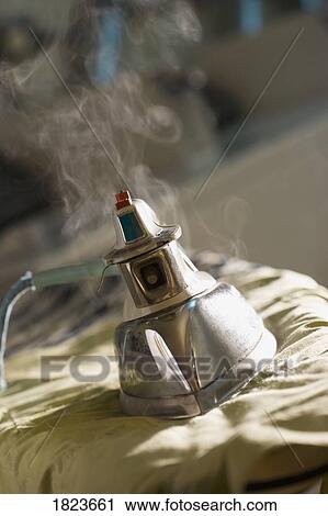Stock Image - Iron on top of an ironing board. Fotosearch