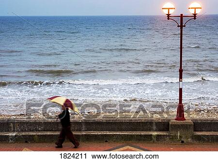 Lady with an umbrella walking along Bridlington prom, Yorkshire, England View Large Photo Image Stock Image - Lady with an umbrella walking along Bridlington prom, Yorkshire, England. Fotosearch