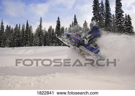 Stock Image - Man jumping a snowmobile. Fotosearch