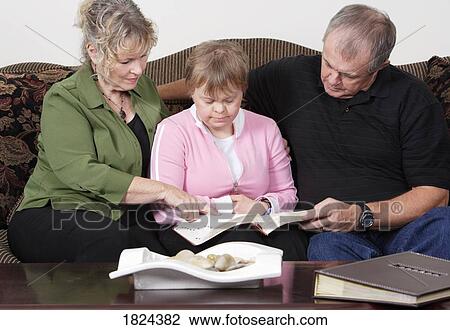 Stock Image - Parents reading with daughter. Fotosearch