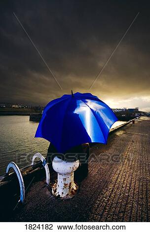 Stock Image - Person with umbrella in stormy skies. Fotosearch