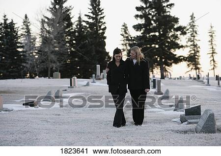 Stock Image - Two woman walking through a cemetery. Fotosearch