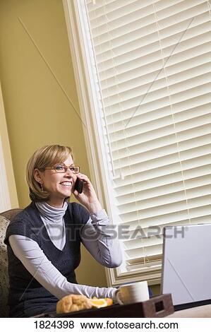 Woman on phone and working on laptop computer View Large Photo Image Stock Photo - Woman on phone and working on laptop computer. Fotosearch