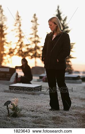 Stock Image - Women visiting grave in cemetery. Fotosearch
