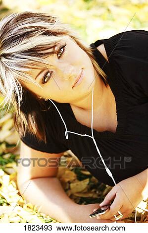 Stock Image - Young woman listening to music. Fotosearch