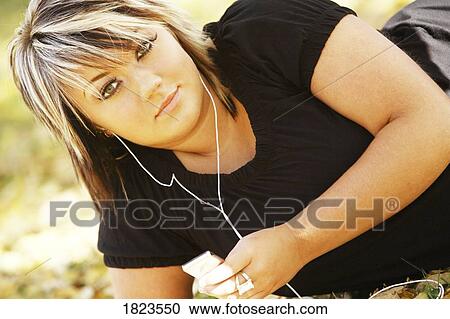 Stock Image - Young woman listening to music. Fotosearch