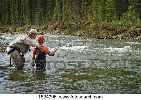 Stock Photograph - Father and sons in a mountain fly fishing river, Nordegg, Alberta, Canada . Fotosearch