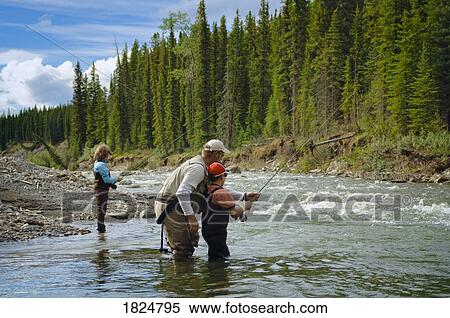 Stock Photography - Father and sons in a mountain fly fishing river, Nordegg, Alberta, Canada . Fotosearch