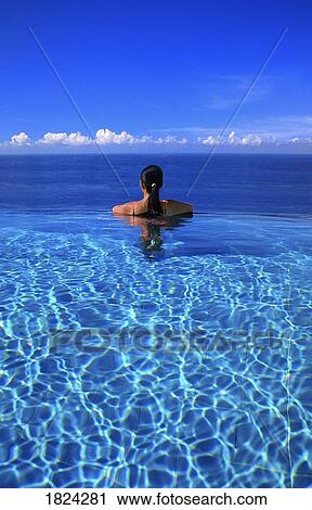 Woman in swimming pool overlooking ocean, Bali, Indonesia View Large Photo Image Stock Image - Woman in swimming pool overlooking ocean, Bali, Indonesia. Fotosearch