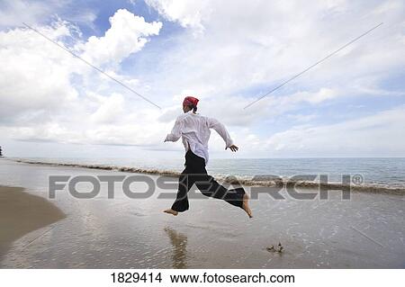 Picture - A man running along the beach. Fotosearch