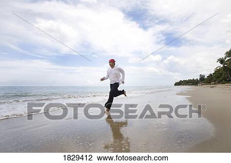 Stock Image - A man running along the beach. Fotosearch