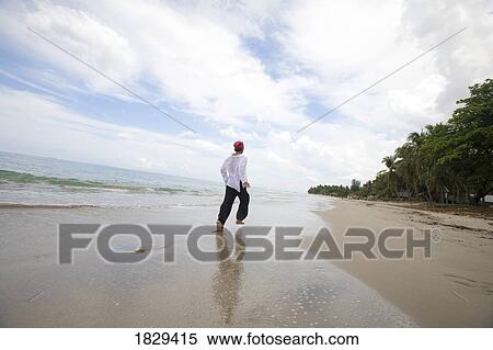 Stock Photography - A man running along the beach. Fotosearch