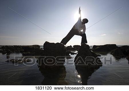Stock Image - A man stretching on a beach in Koh Lanta, Thailand. Fotosearch