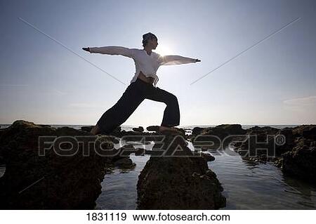 Stock Photo - A man stretching on a beach in Koh Lanta, Thailand. Fotosearch