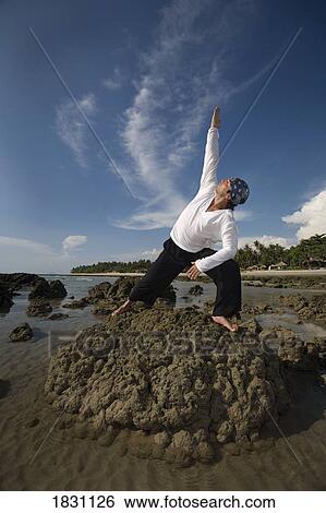 A man stretching on a rocky beach in Koh Lanta, Thailand View Large Photo Image Stock Photograph - A man stretching on a rocky beach in Koh Lanta, Thailand. Fotosearch