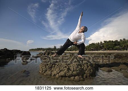 A man stretching on a rocky beach in Koh Lanta, Thailand View Large Photo Image Stock Photography - A man stretching on a rocky beach in Koh Lanta, Thailand. Fotosearch