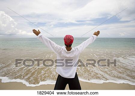 Picture - A man with arms outstretched on a beach in Koh Lanta, Thailand. Fotosearch