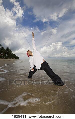 Stock Image - A man with arms outstretched on a beach in Koh Lanta, Thailand. Fotosearch