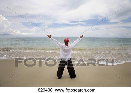 Stock Photo - A man with arms outstretched on a beach in Koh Lanta, Thailand. Fotosearch