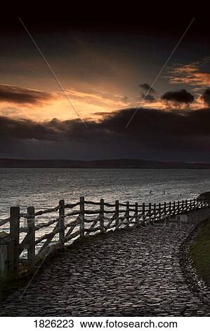 Stock Image - A stone path along the water, Holy Island, Berwick, Northumberland, England. Fotosearch