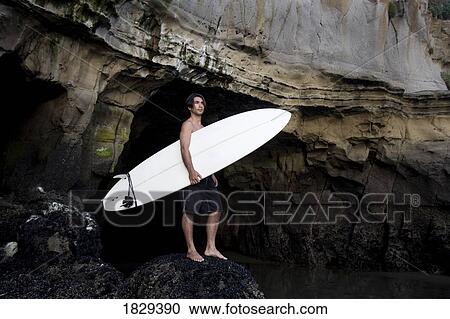 Stock Image - A surfer on Muriwai Beach, New Zealand. Fotosearch