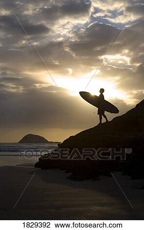 Stock Image - A surfer on Muriwai Beach, New Zealand. Fotosearch