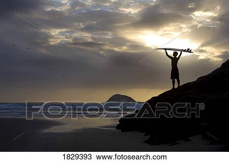 Stock Image - A surfer on Muriwai Beach, New Zealand. Fotosearch